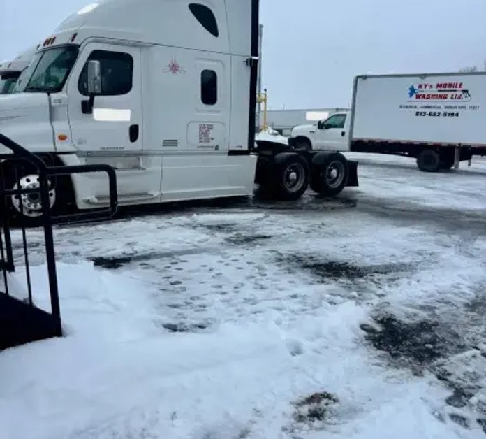 A picture of a man pressure washing a transport truck
